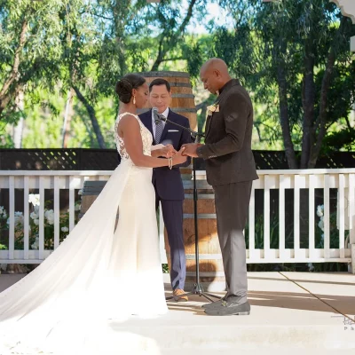 Bride and groom exchanging rings during outdoor wedding ceremony under a white gazebo