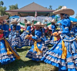 A group of women in blue dresses and hats dancing.