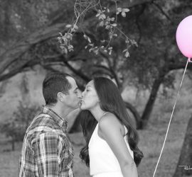 © 2019 RKS Photography | https://rksshots.com A man and woman kiss outdoors near trees, with a pink balloon floating beside them.