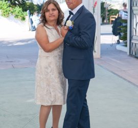 A woman and a man in formal attire dance together outdoors at a daytime event.
