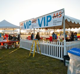 Outdoor VIP area for the National Multiple Sclerosis Society event with tents, tables, and people setting up.